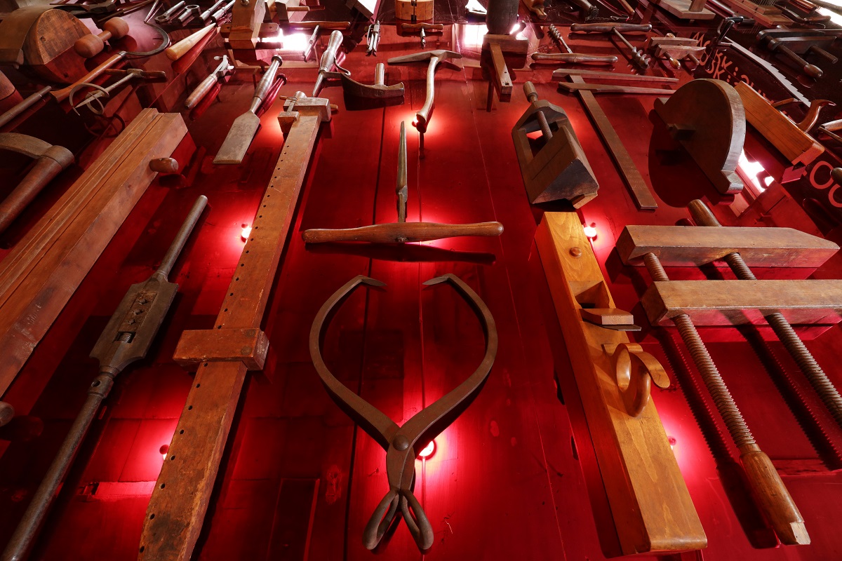 A display of tools on a red wall.