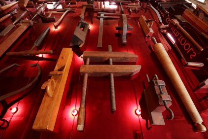 A wall of tools on a red wall.