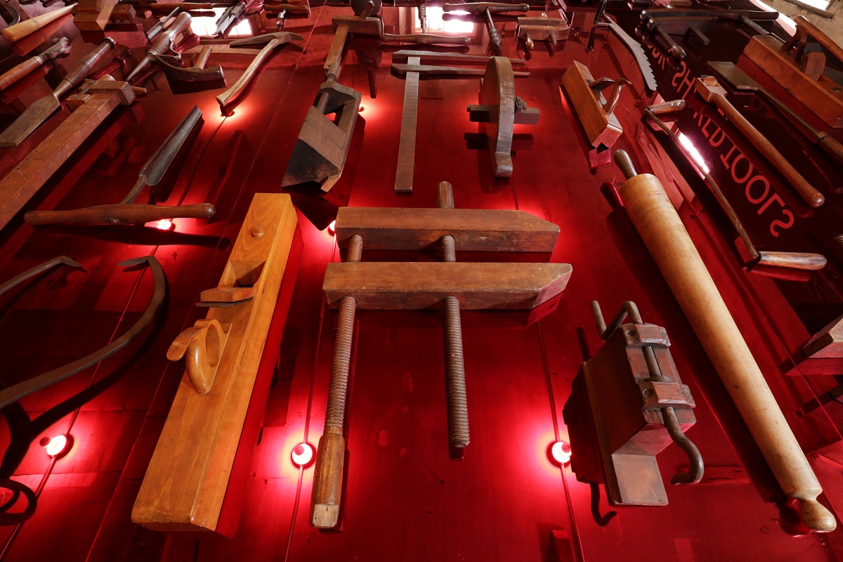 A wall of tools on a red wall.