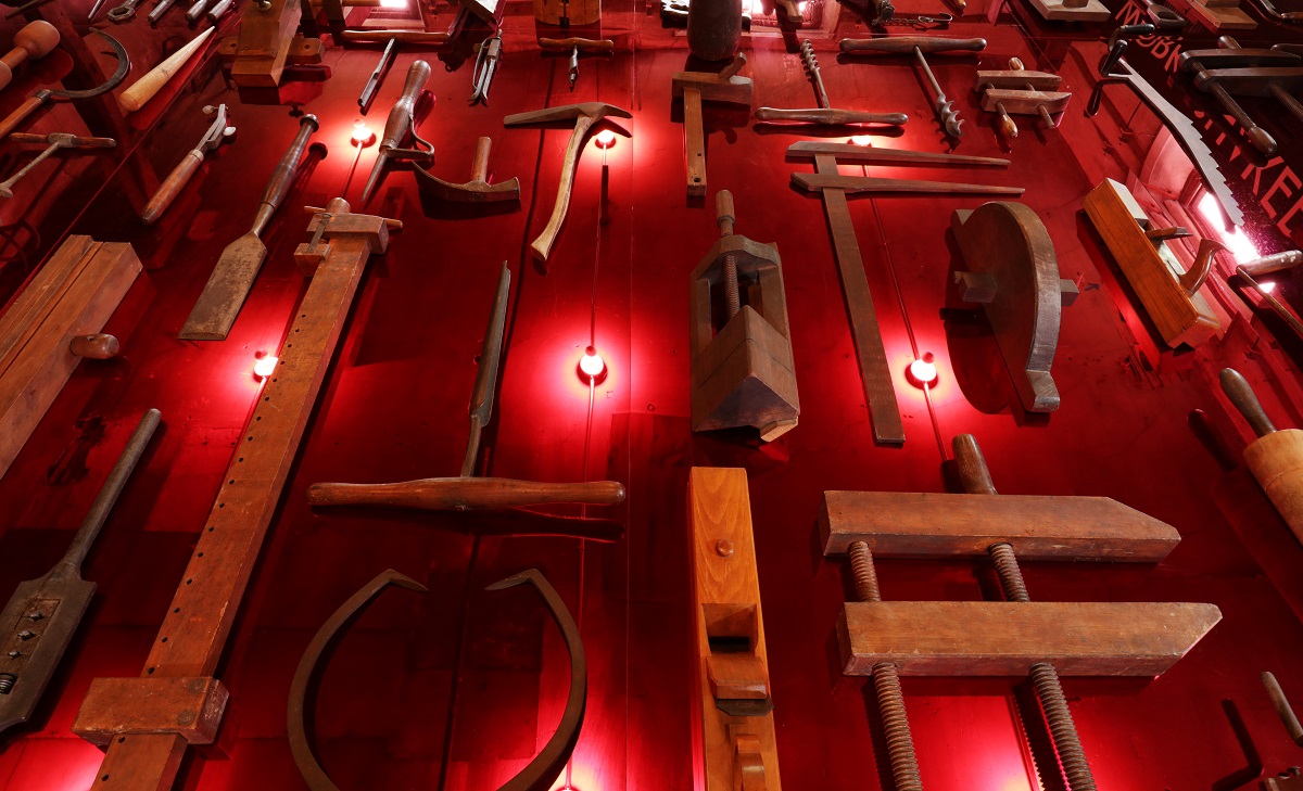 A wall of tools on a red wall.