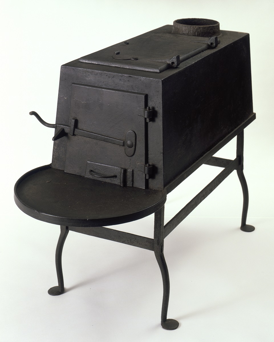 A black stove on a table with a lid.