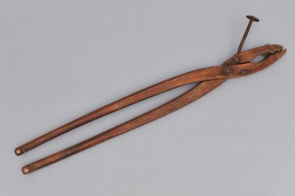 A pair of wooden pliers on a gray background.