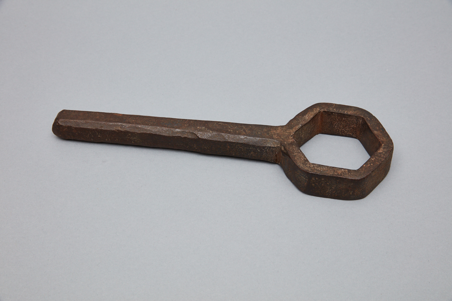 A wooden hex key on a gray surface.