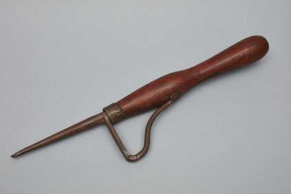 A tool with a wooden handle on a gray surface.