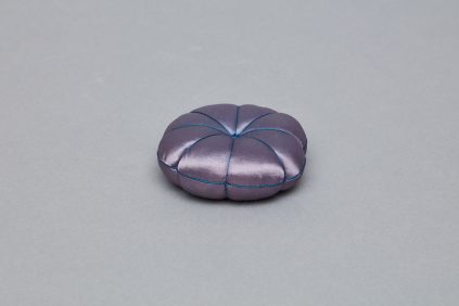 A small purple pillow on a grey surface.