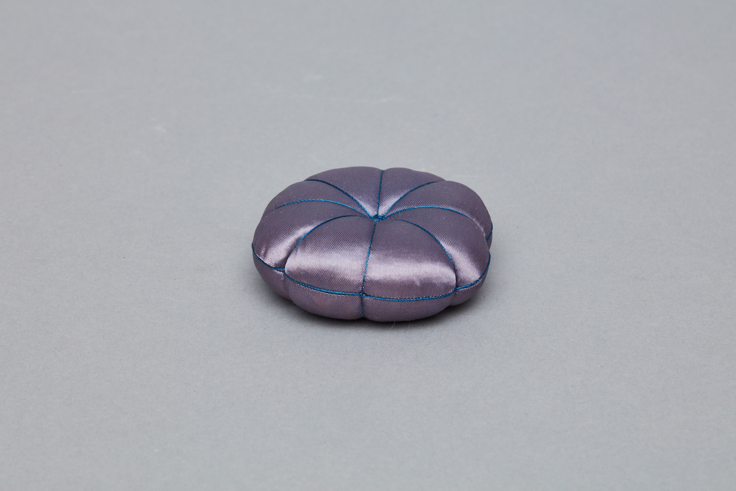 A small purple pillow on a grey surface.