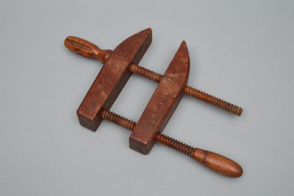 A pair of wooden vises on a gray surface.