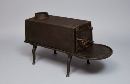 A small metal stove with a tray on it.