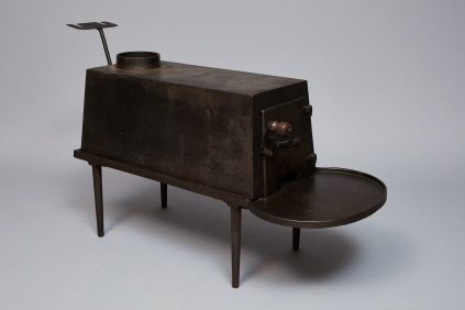 A black metal stove with a tray on top.
