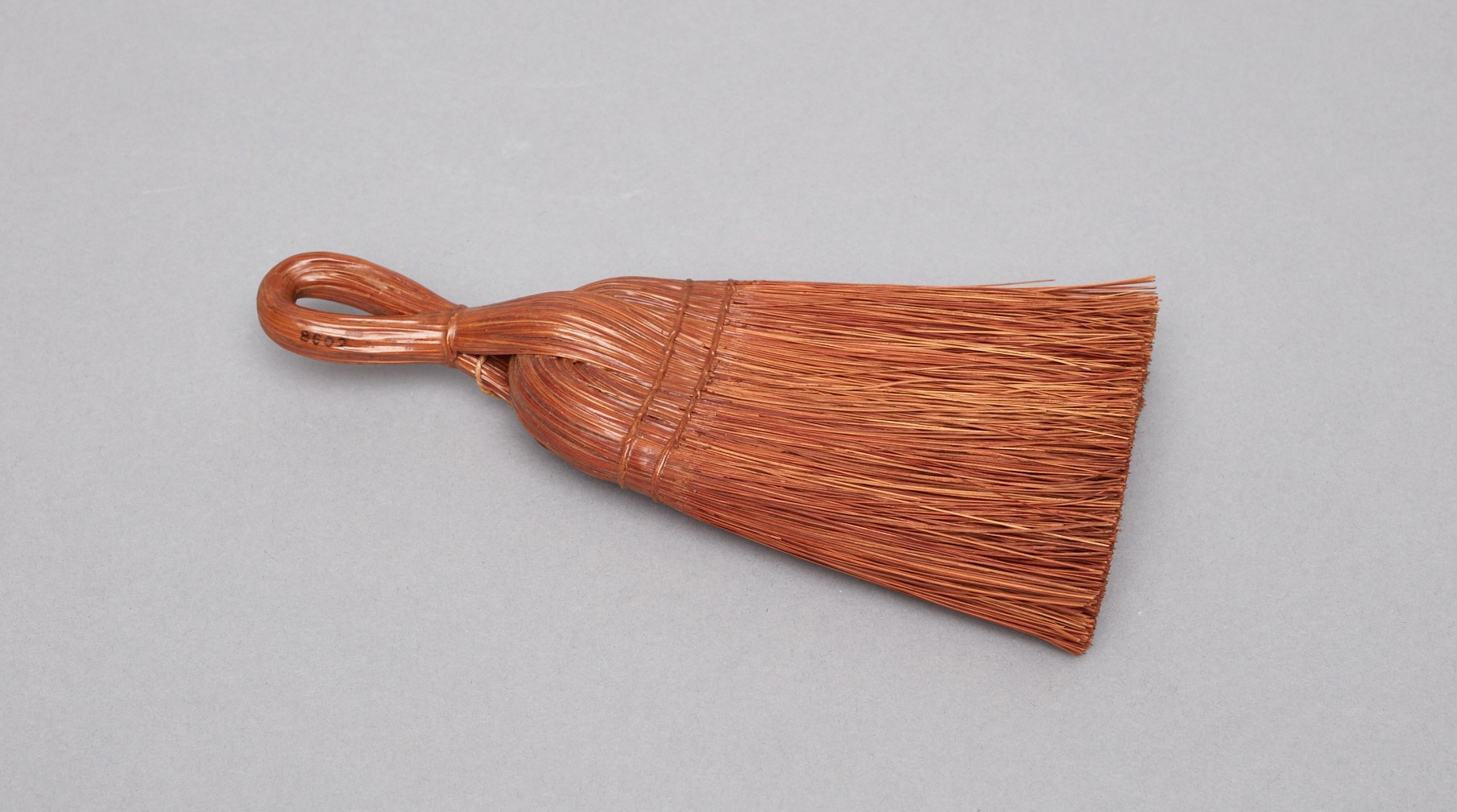 A brown broom with a wooden handle.