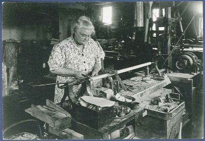 An old black and white photo of a woman working in a workshop.