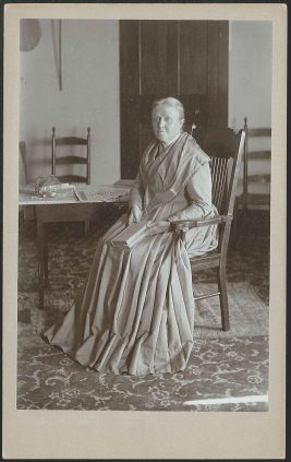 An old photograph of a woman sitting in a chair.