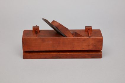 A wooden box with a knife on top.