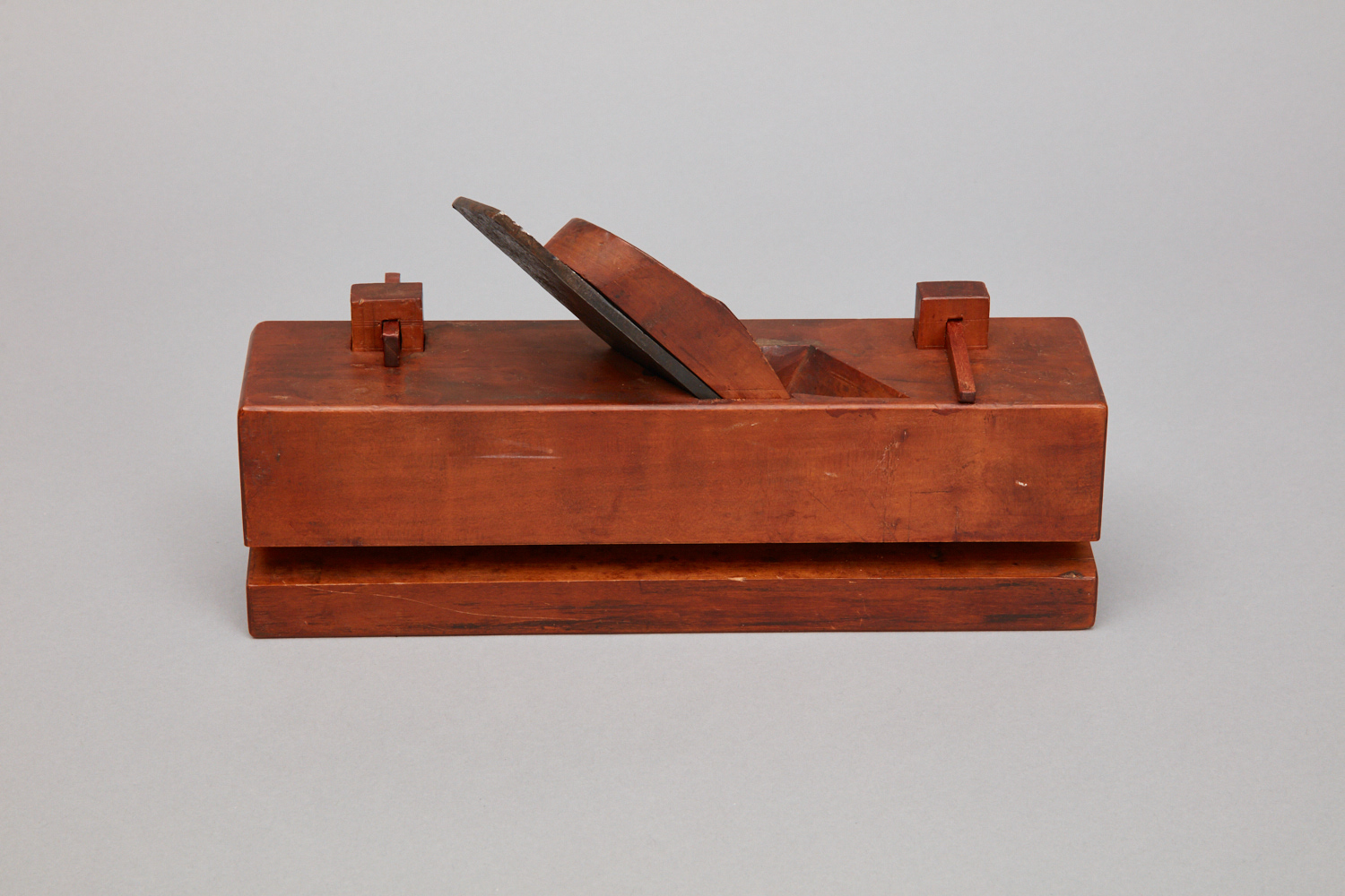 A wooden box with a knife on top.