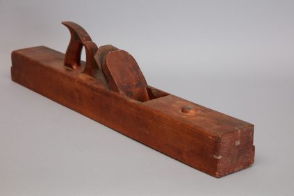 A wooden planer is sitting on a gray surface.