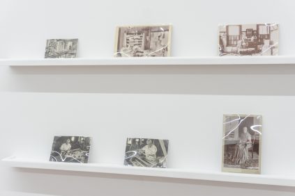 A white shelf with several photographs on it.