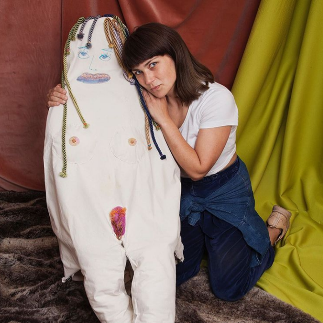 A woman posing next to a stuffed doll.