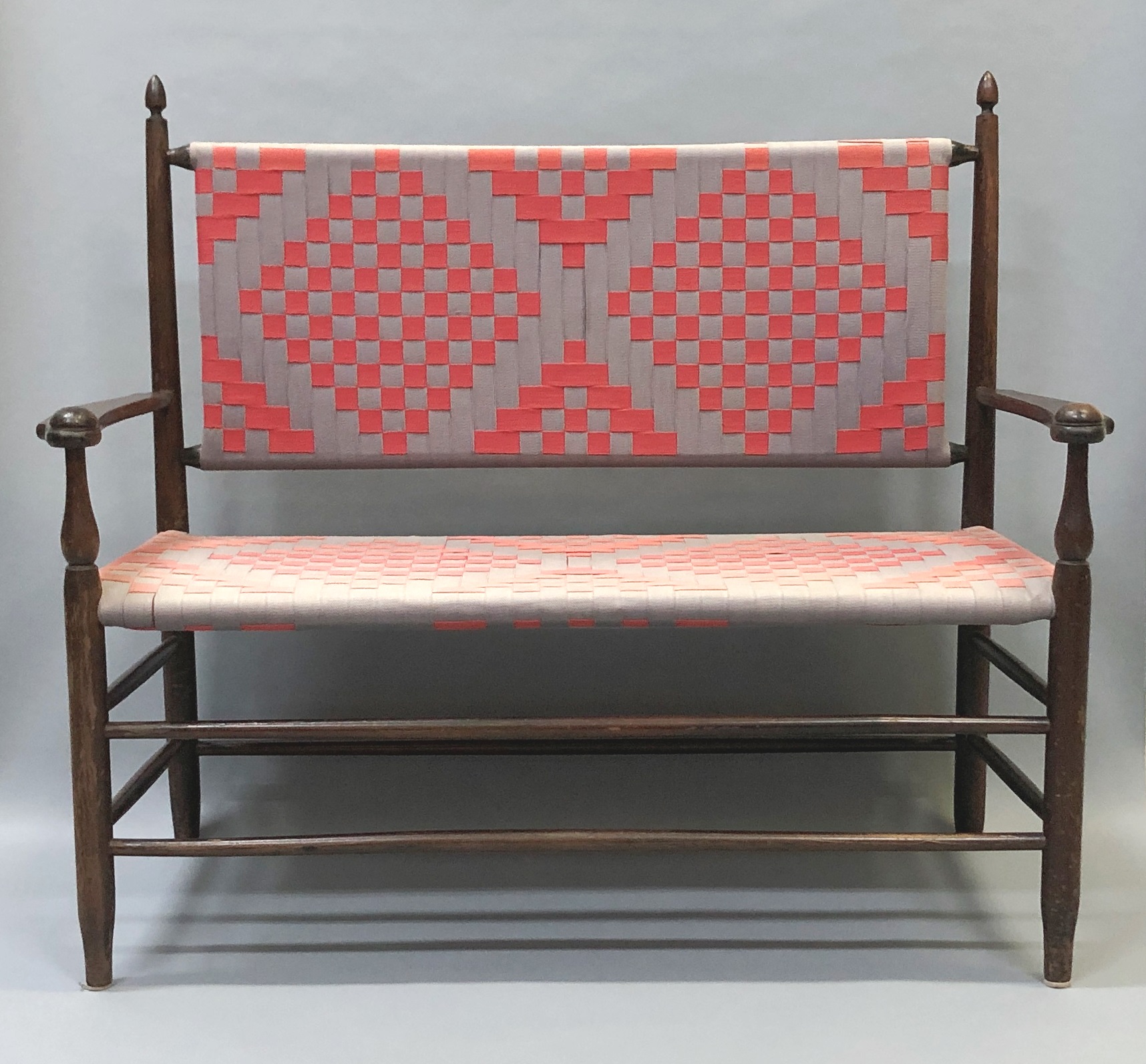 A bench with a pink and gray patterned seat.