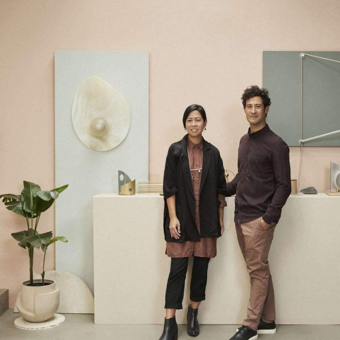 A man and woman standing in front of a pink wall.