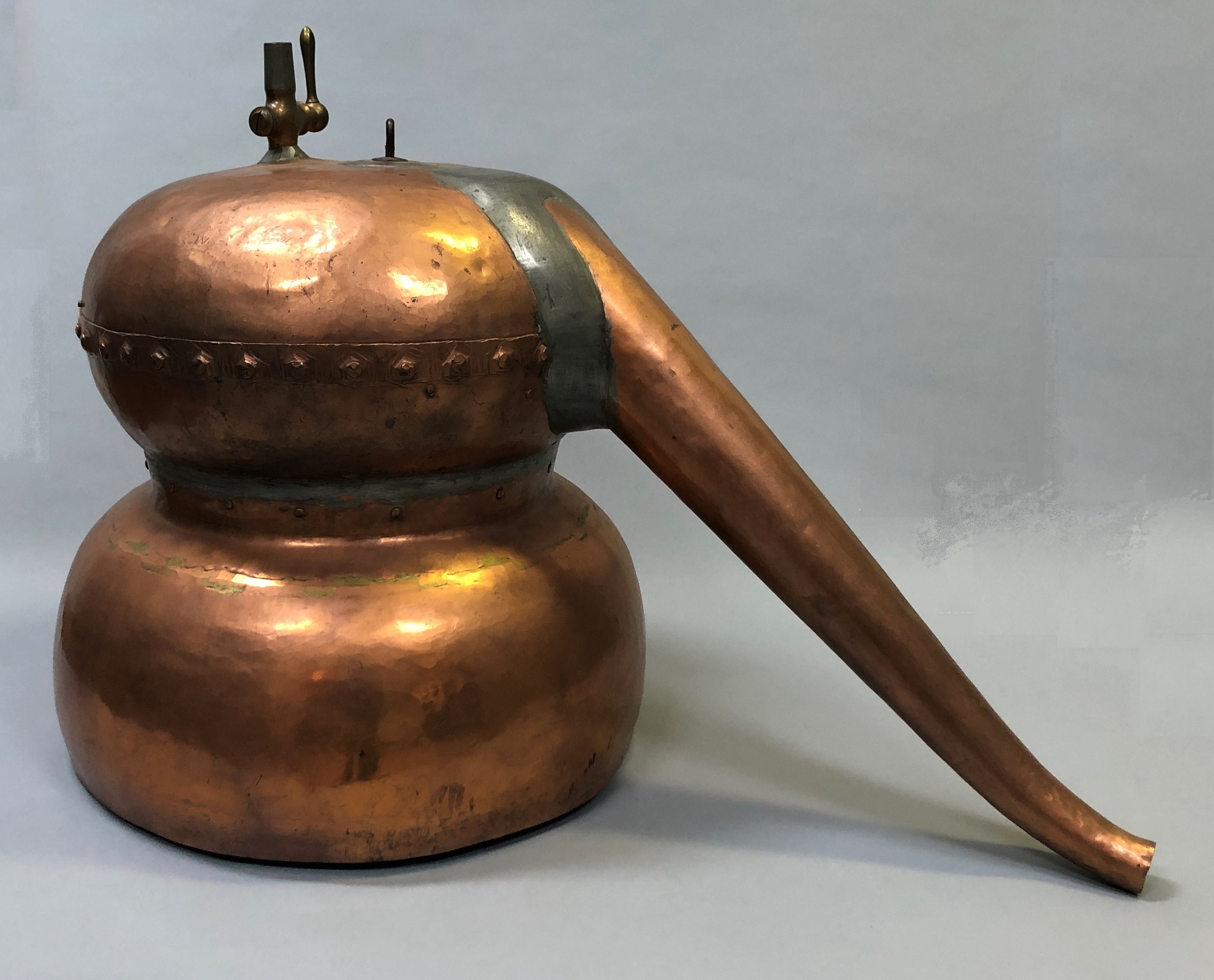 A copper pot with a long spout.