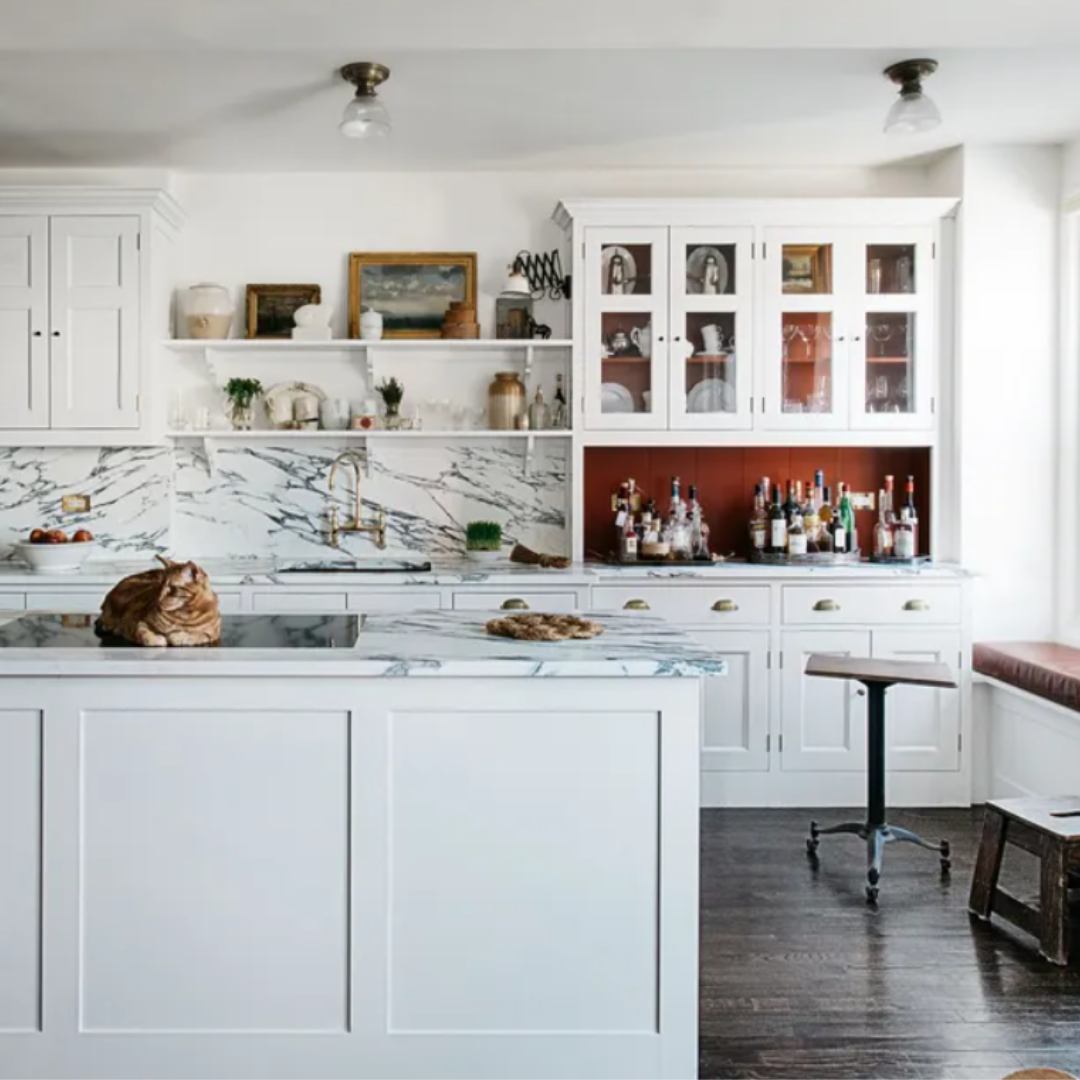 A white kitchen with marble counter tops.