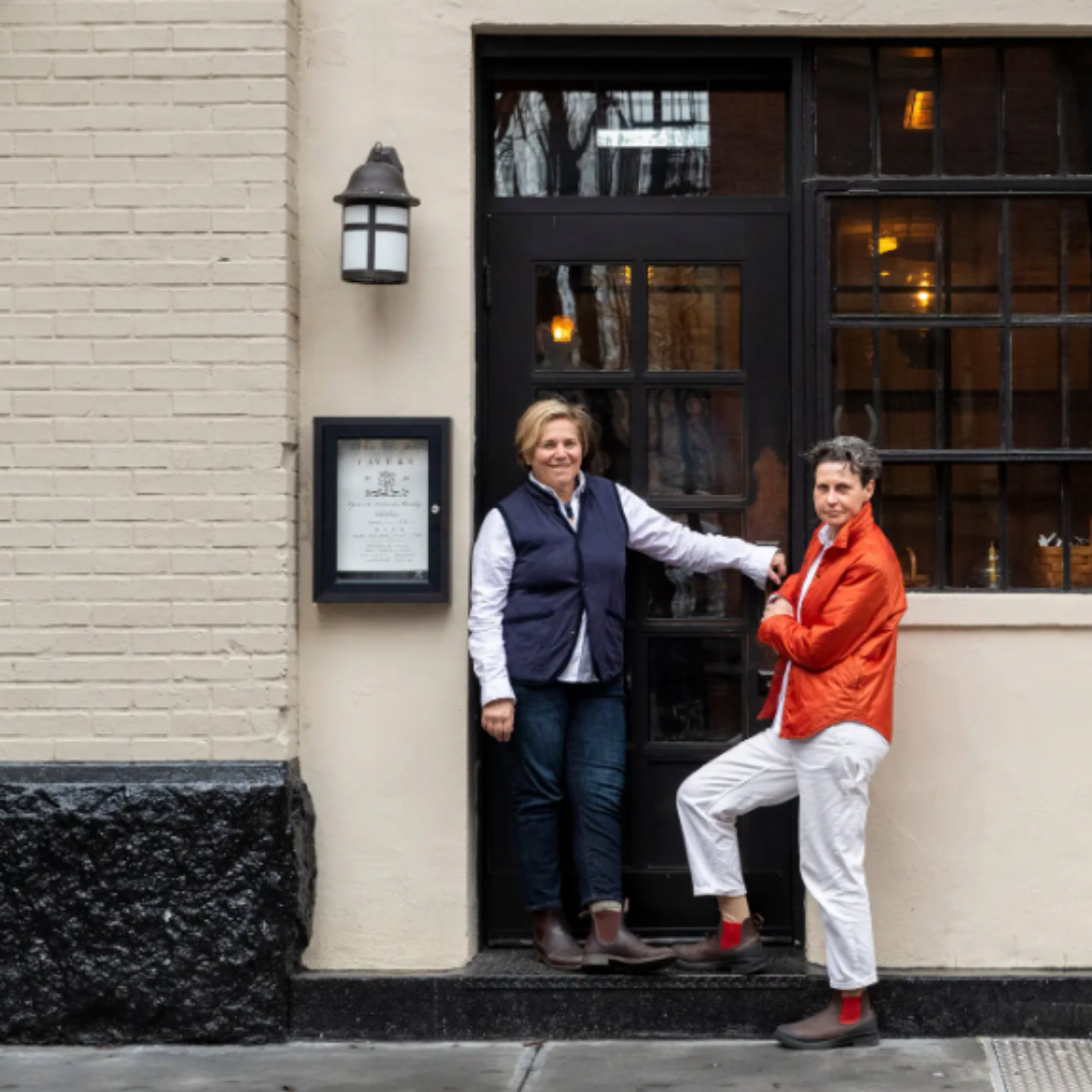 Two women standing on the steps of a restaurant.
