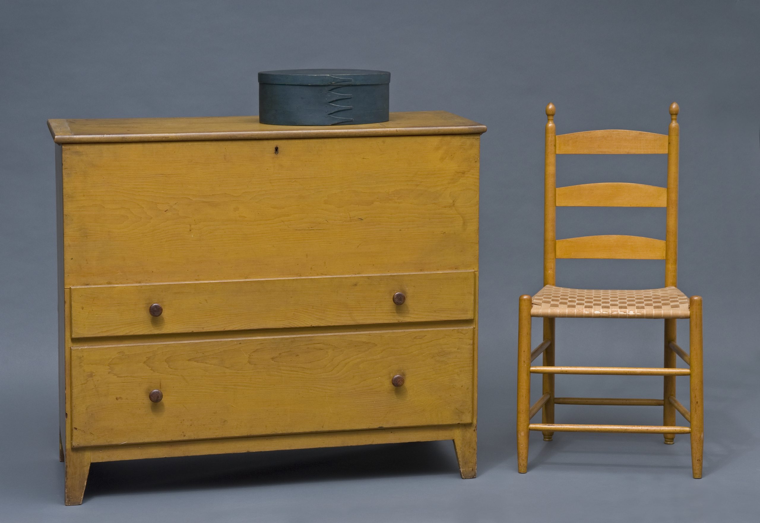 A yellow dresser and chair next to a gray background.