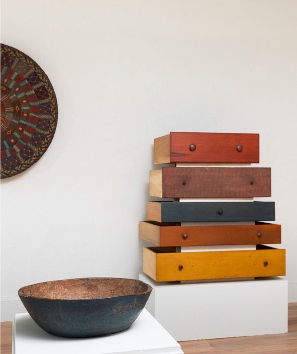 A stack of wooden drawers and a bowl in a room.