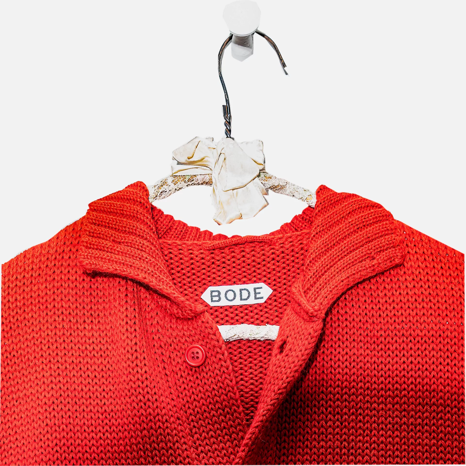 A red Bode sweater hanging on a hanger.