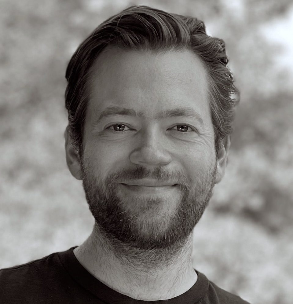 A black and white photo of a person smiling.