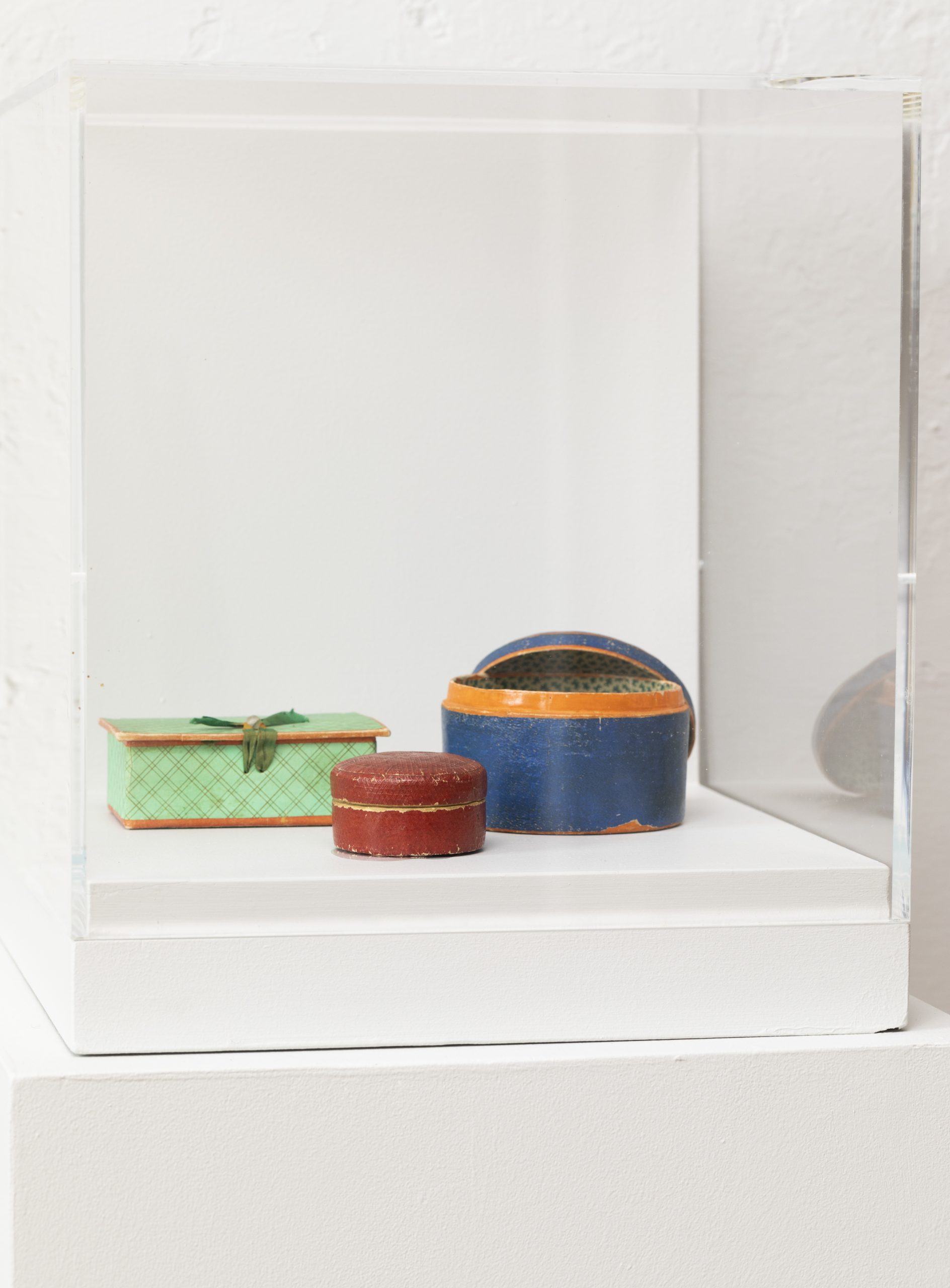 Various colorful vintage tins on display inside a clear case.