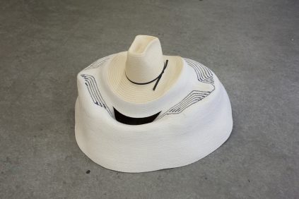 A white sombrero with a black band on a gray surface.